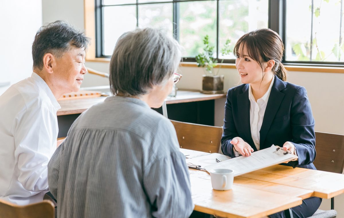 柏原市の長屋の買取について相談するご夫婦と株式会社GEEZの担当者